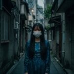 Imagen de Kuchisake-onna, la leyenda japonesa de terror, con su característica máscara quirúrgica en una calle oscura de Tokio. Perfecta para ilustrar relatos de miedo y leyendas urbanas japonesas. #kuchisakeonna #leyendajaponesa #terrorjapones